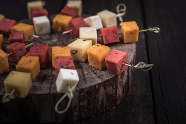 Many kinds of cheeses on wooden end of a tree