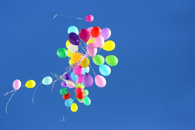 Many multicolored balloons flying in the blue sky