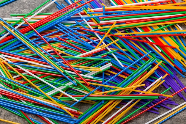 many multicolored plastic tubes for cocktail on Colored background top view