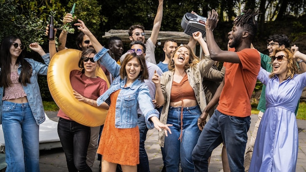 Many multiethnic young people having fun dancing music outside in the garden