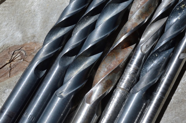 many old drills lie on a plank wooden background. close-up.