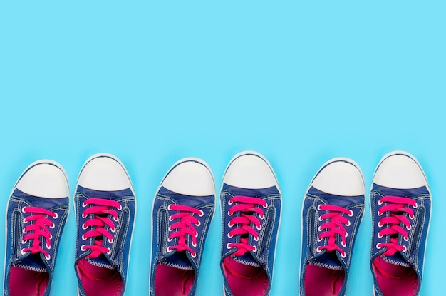 Many old pair of blue sneakers on light blue background