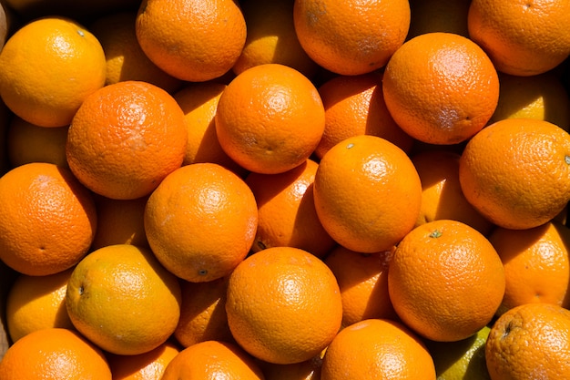 Many orange fruits at a market during sunny day.