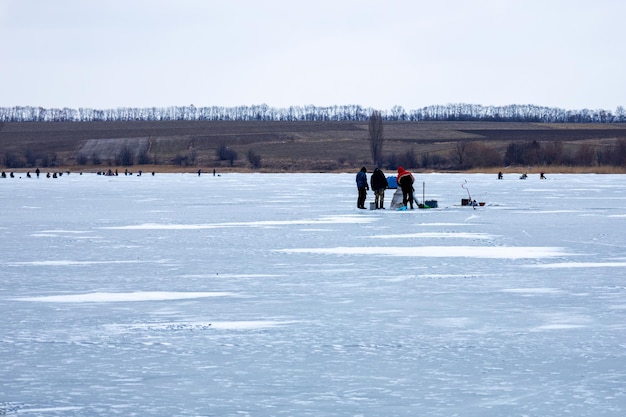 Many people on ice winter fishing frozen river in winter ice fishing