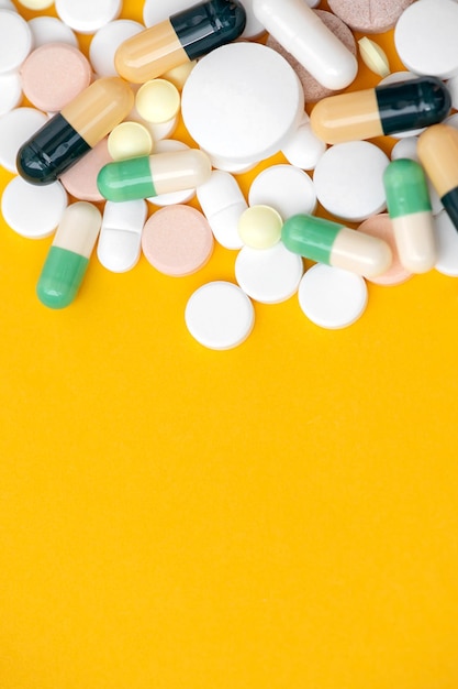 Many pills and dietary supplements on a yellow background. Health care, pharmaceutical picture.