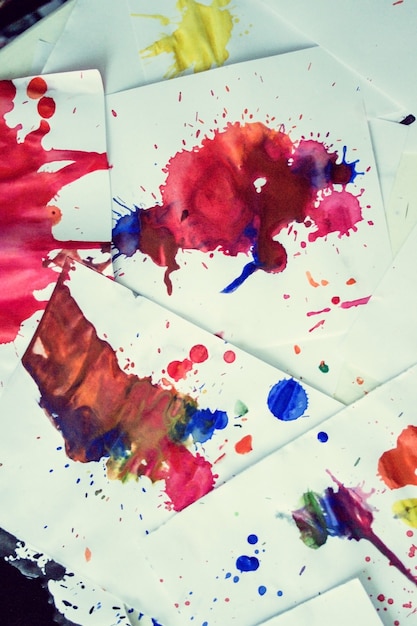 Many red colored blots on white paper with streaks