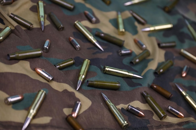 Many rifle bullets and cartridges on dark camouflage background