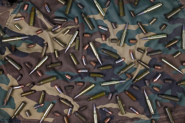 Many rifle bullets and cartridges on dark camouflage background