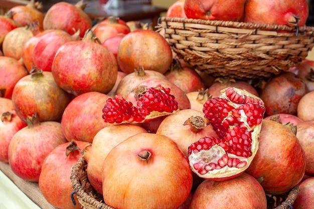 Many ripe pomegranates on counter, on top lies open pomegranate with red seeds. Flawless grenades for packaging or banner. Horizontal photo.