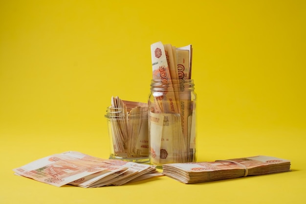 Many russian bank notes in a glass jar isolated on yellow background