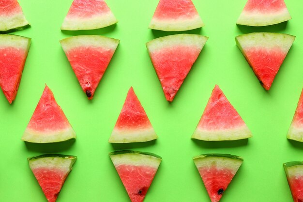 Many slices of watermelon on green, top view