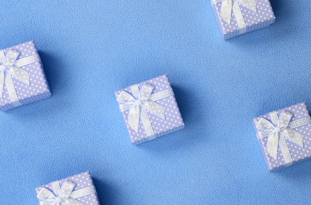 Many small gift boxes in blue color with a small bow lies on a blanket 