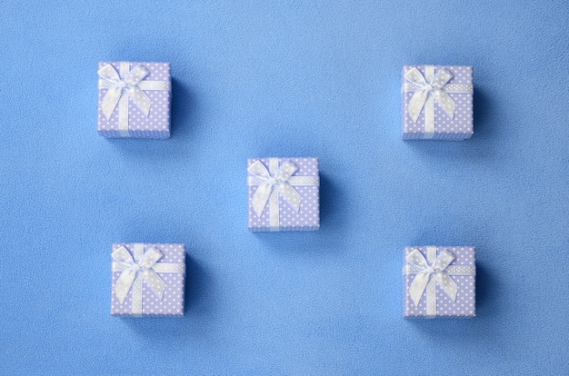 Many small gift boxes in blue color with a small bow lies on a blanket 