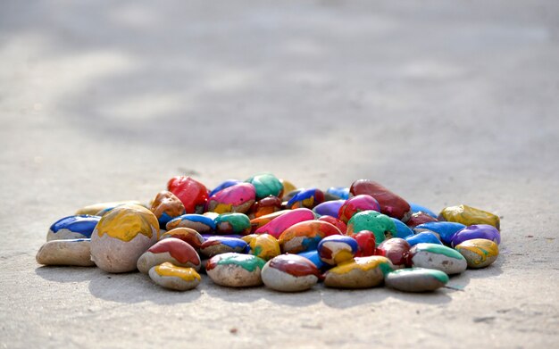 Many small pebbles covered with multicolored paint lie on the surface close-up