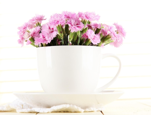 Many small pink cloves in cup on wooden background