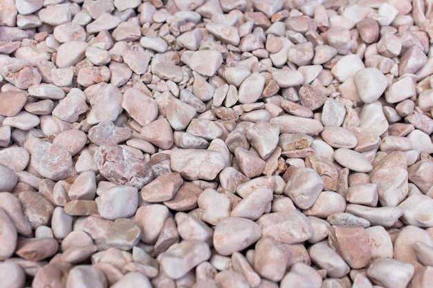 Many small polished  decorative stones used in landscape design with pink color tint.