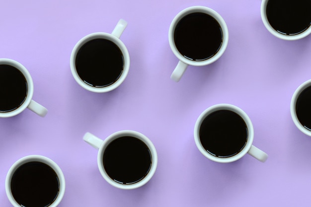 Many small white coffee cups on texture background of fashion pastel violet color