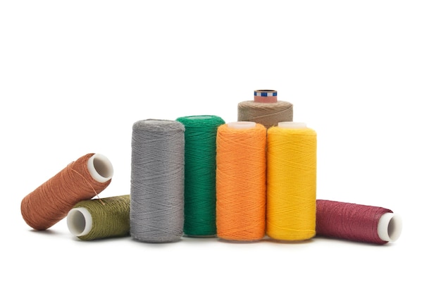 Many spools of thread of different colors scattered on a white background