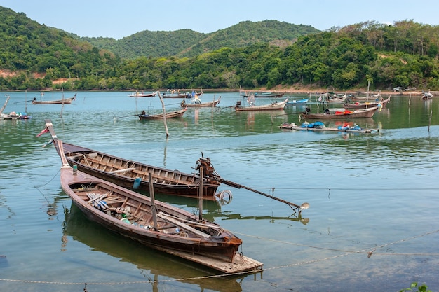 Many tethered long fishing boats with long propellers in the bay