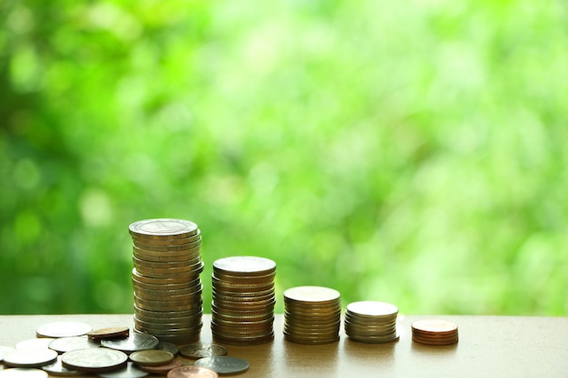 Many Thai coins on wooden table on green garden background concept growth