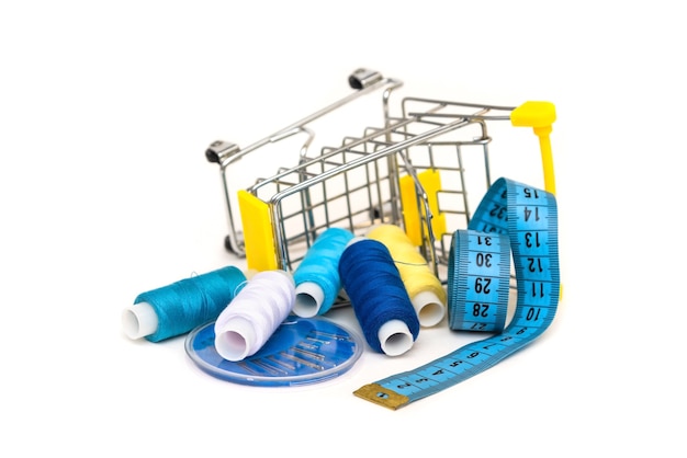 Many threads lie in the cart on a white background with a rubber ruler and needles.