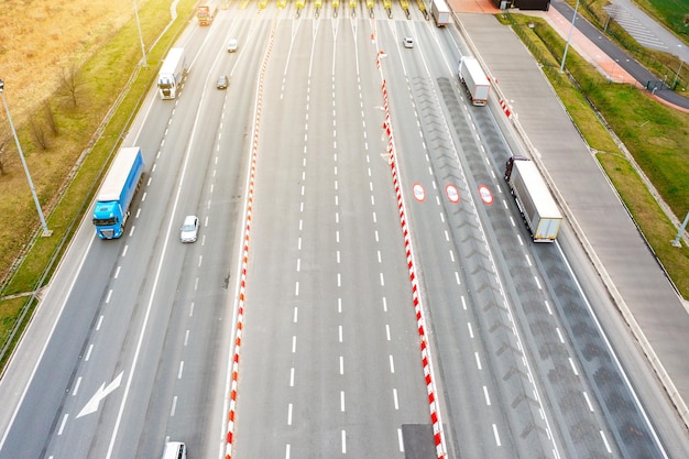 Many trucks are moving along the highway crossing road between the fields drone view