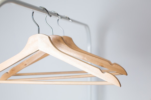 Many wooden hangers on a rod, isolated on white wall background.