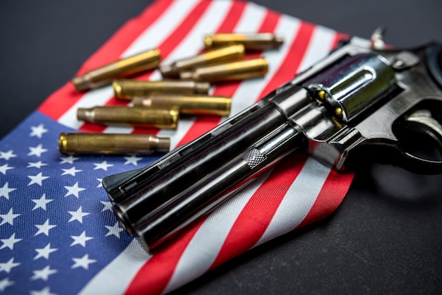 Many yellow bullets and a revolver gun on the flag of United States isolated on black table