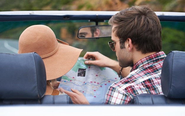 Map travel and back of couple in a car for driving to vacation adventure or holiday destination Reading navigation guide and young people on journey in vehicle for weekend road trip together