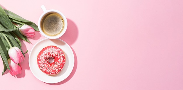 March 8 International Women's Day number eight consisting of a cup of coffee and a donut with a pink filling next to pink tulips on a pink background space for text