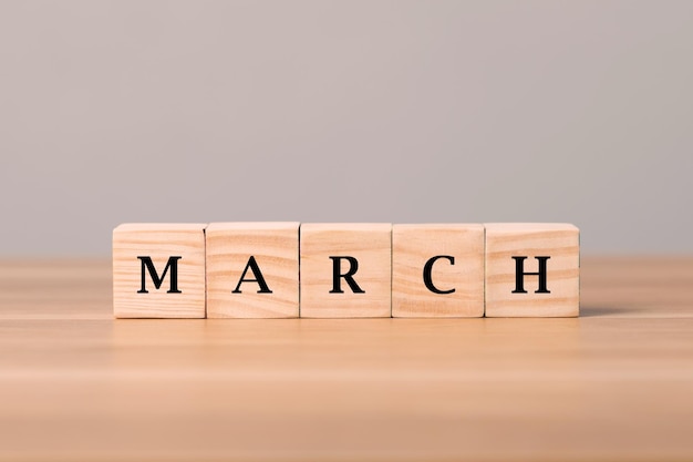 March write on wooden blocks arranged on wooden desk with grey wall background