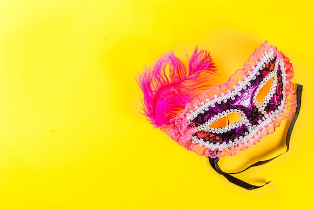 Mardi gras  with holiday mask, on bright yellow    copyspace top view