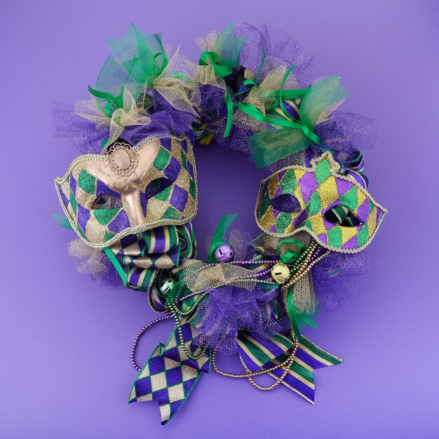 Mardi gras wreath on purple background with mardi gras mask. Top view