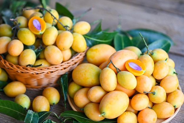 Marian plum fruit and leaves in basket on wooden background tropical fruit Name in Thailand Sweet Yellow Marian Plum Maprang Plango or Mayong chid