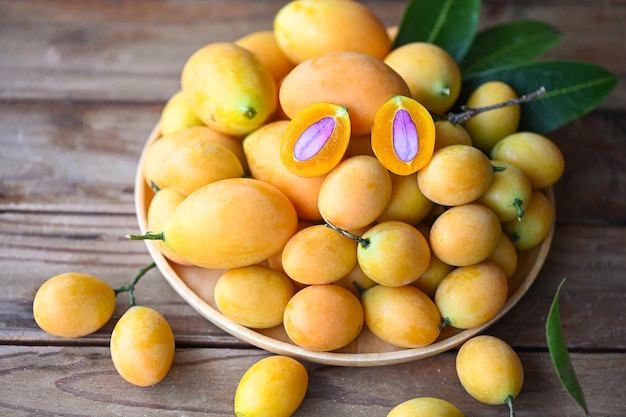 Marian plum fruit and leaves in plate on wooden background tropical fruit Name in Thailand Sweet Yellow Marian Plum Maprang Plango or Mayong chid