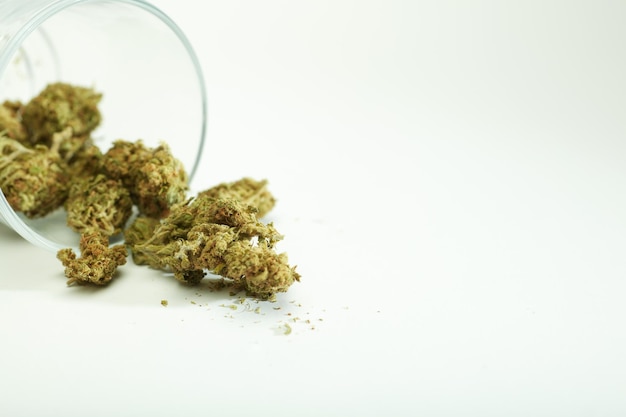 marijuana buds coming out of glass container on white background space for text