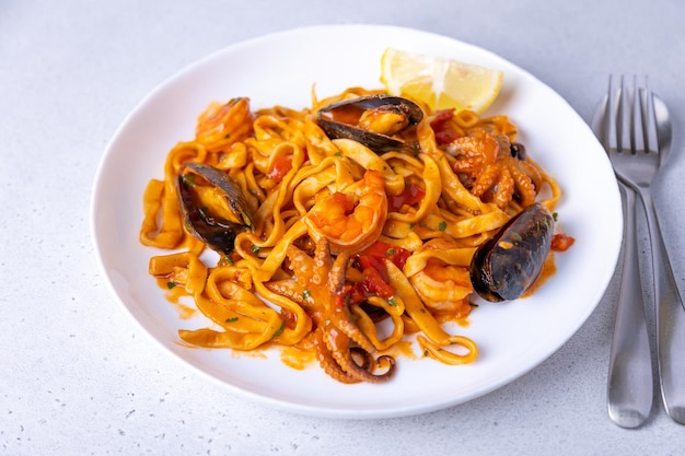 Marinara pasta with shrimps octopus and mussels Homemade noodles with seafood in tomato sauce Traditional Italian dish Selective focus closeup