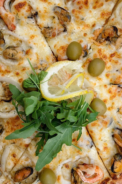 Marinara pizza with squid mussels shrimp olives and lemon top view Closeup