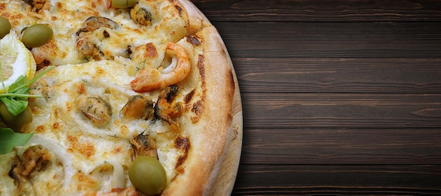 Marinara pizza with squid mussels shrimp olives and lemon on a wooden round board