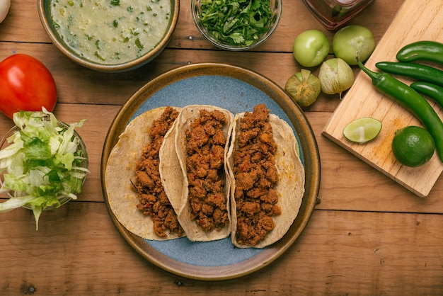 Marinated beef tacos bowl with salsa verde and vegetables on a wooden table Tacos de adobada