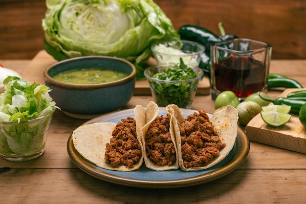 Marinated beef tacos bowl with salsa verde and vegetables on a wooden table Tacos de adobada