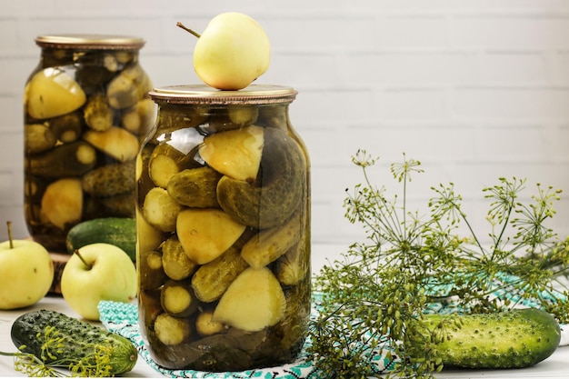 Marinated cucumbers with apples in jars are arranged on a white background Harvest for the winter