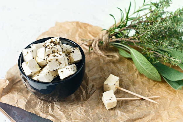 Marinated feta in a plate on a wooden board with spices on a white background