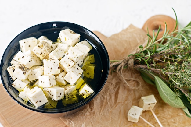 Marinated feta in a plate on a wooden board with spices on a white background