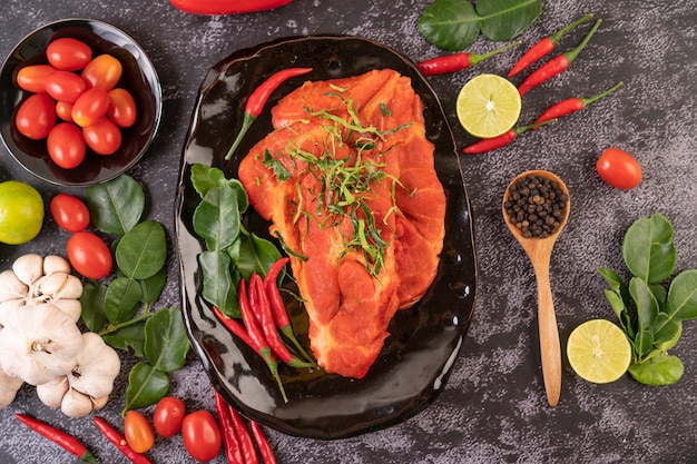 Marinated pork used in cooking complete with chili peppers Kaffir lime leaves in a black plate