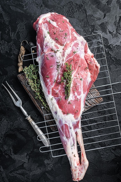 Marinated raw lamb mutton Leg Thigh with thyme and spices Black background Top view