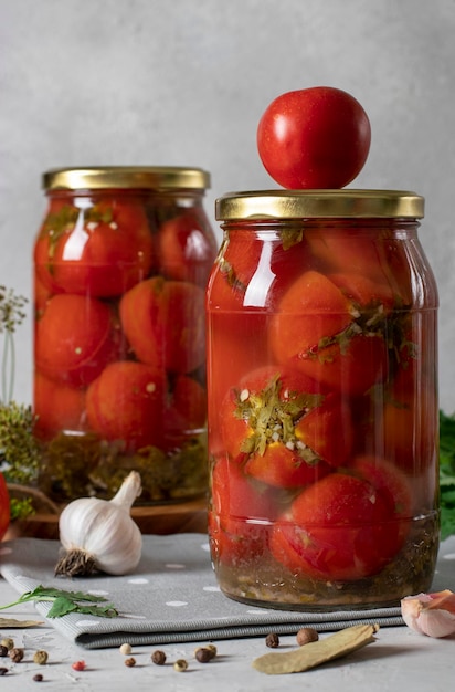 Marinated tomatoes with cilantro in jars for the winter on light gray background