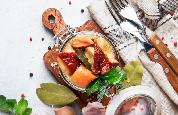 Marinated white mushrooms in jar with spices food cooking concept gray kitchen table background top view place for text