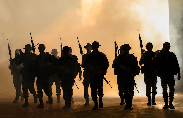 Marines team in action, surrounded fire and smoke, shooting with assault rifle and machine gun, attacking enemy