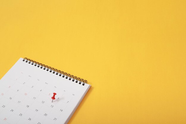 Photo mark the event day with a pin thumbtack in calendar concept for busy timeline organize scheduleappointment meeting reminder planning business meeting or travel holiday planning concept soft focus